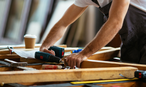 A close up of a power drill being used on lumber