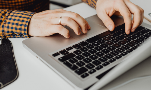 Hands typing on a laptop